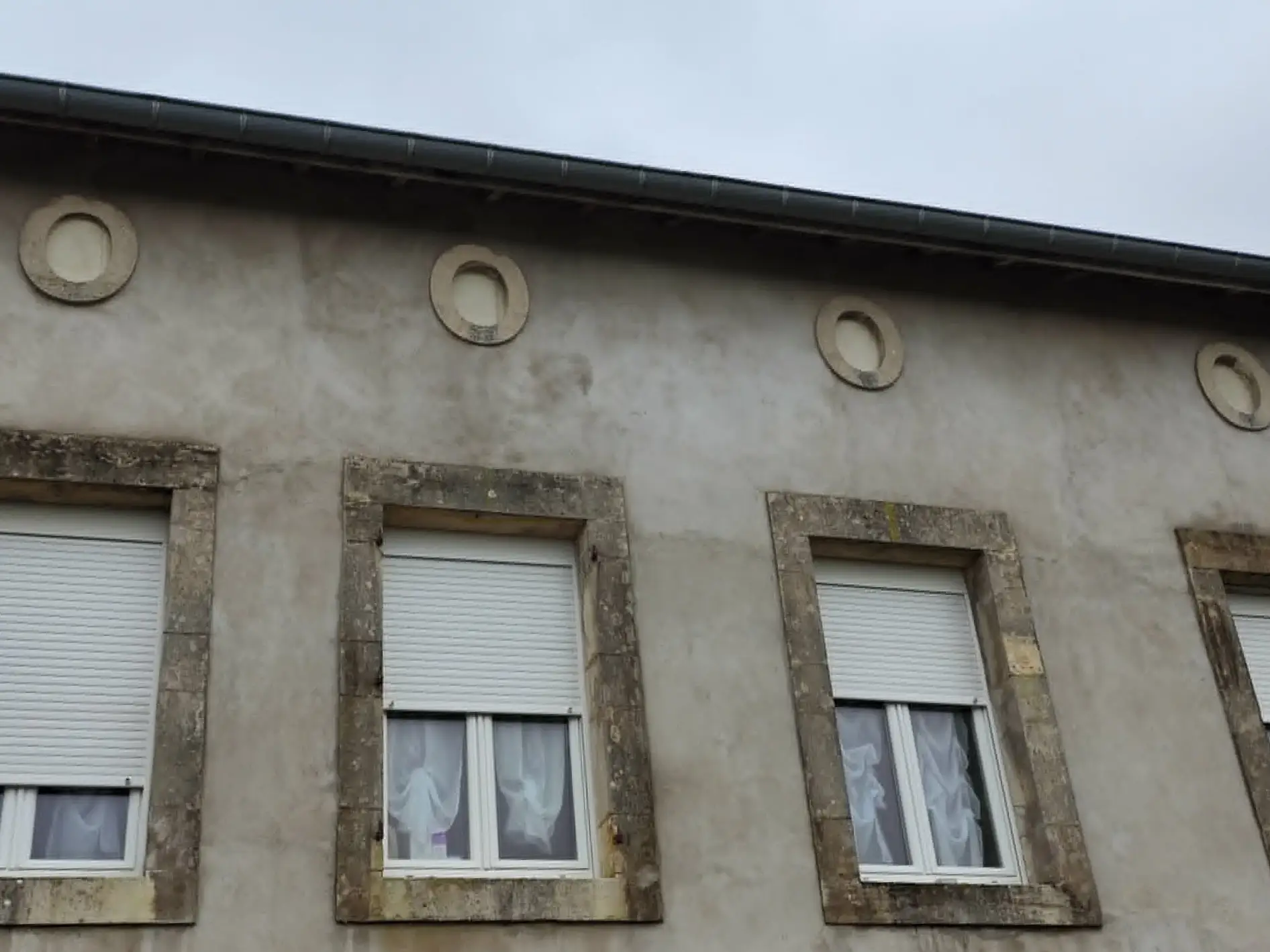 Ouvertures circulaires rebouchées en partie haute de la façade